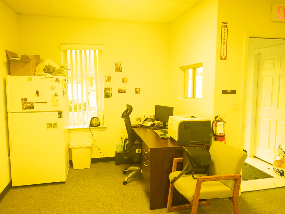 A view of an office room under the 450 tint, creating a warm and intense yellow hue across the image, impacting the visibility and color perception of furniture and room details.