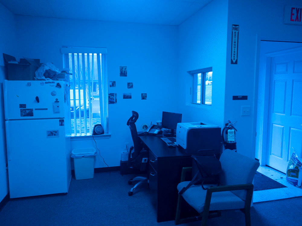 A view of an office room under a cool blue tint, applied by the Noir 26 filter, casting a serene and intense blue shade over the image, significantly altering the color perception of furniture and room elements.