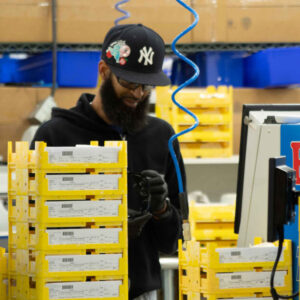 lab-staff-16 Chadwick Optical staff member works in the lab, surrounded by yellow trays of lenses, focusing on organizing or preparing lenses for processing.