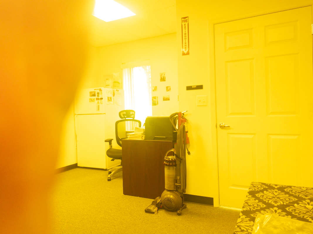 A view of an office room under a yellow tint, applied by the Noir 465 filter, creating a warm and intense yellow hue across the image, affecting the visibility of furniture and room details.