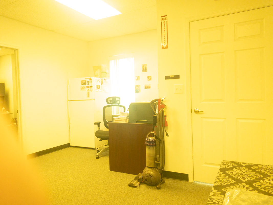 An office interior under the Noir 58 tint, with a bright yellow filter that saturates the room in a yellow glow, affecting all visible items, including walls, door, and desk, with high brightness.