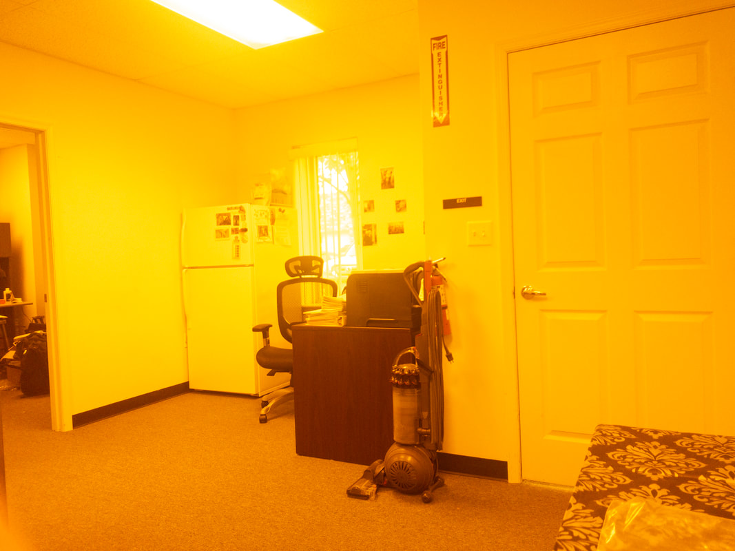 Office room with a deep orange tint from the Noir 60 filter, casting a strong orange color across the scene, which changes the appearance of the walls, furniture, and details with a heavy, warm overlay.