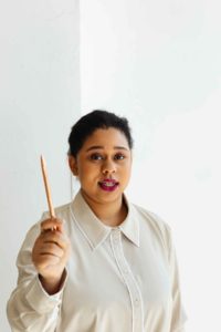 pencil Woman with dark hair holding a pencil upright in front of her.